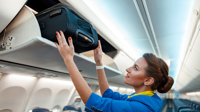 Flight attendant loading a suitcase