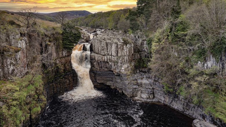 High Force Waterfalls surrounded by a rocky gorge at sunset in Teesdale County, England