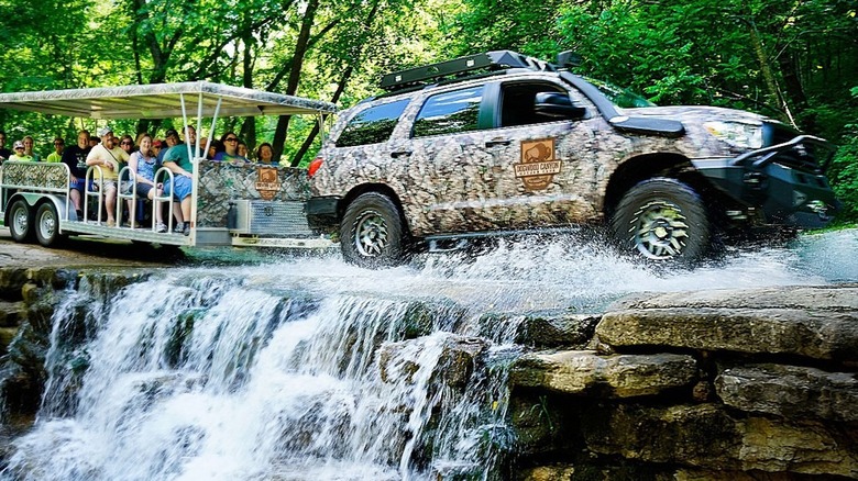 Wildlife Tour driving over a small waterfall pulling a tram full of tourists