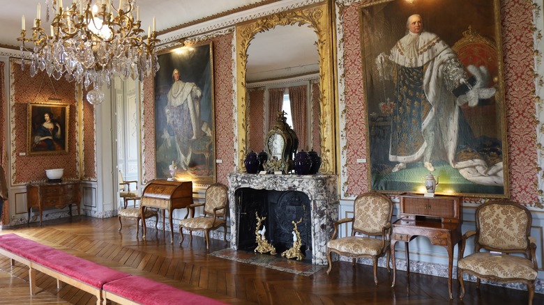 Luxurious gallery room with royal paintings, fireplace, and a chandelier