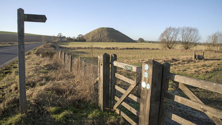 Signpost and wooden gate leading to ancient mound in Wiltshire, England