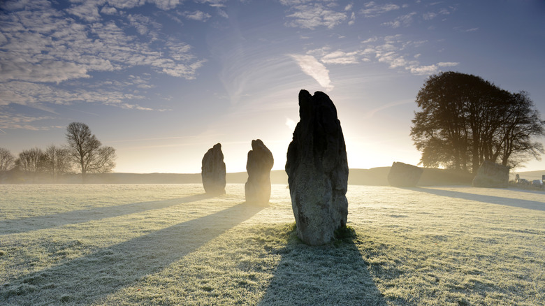 Giant stones standing in grassy plain in misty morning light at Avebury World Heritage Site in England