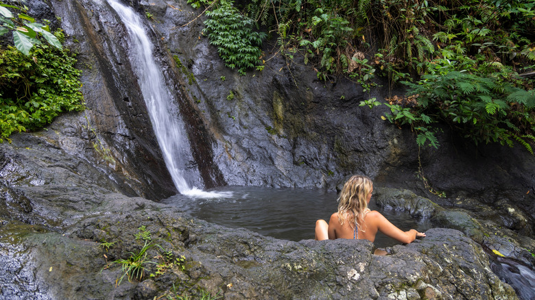 woman soaking waterfall pool