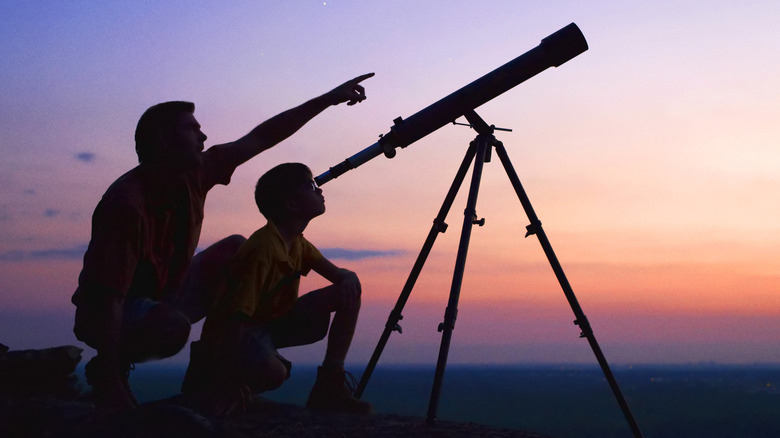 Man and child looking through telescope