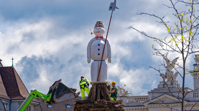 The preparations to get the Böögg ready for burning and explosions as it stands on a pyre