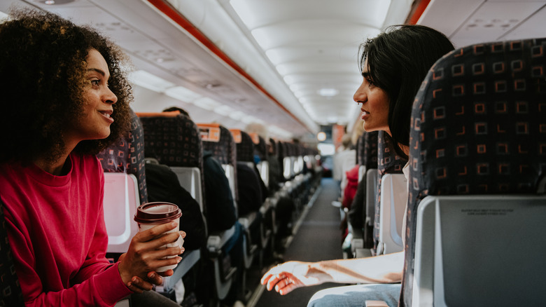 two women speaking on airplane