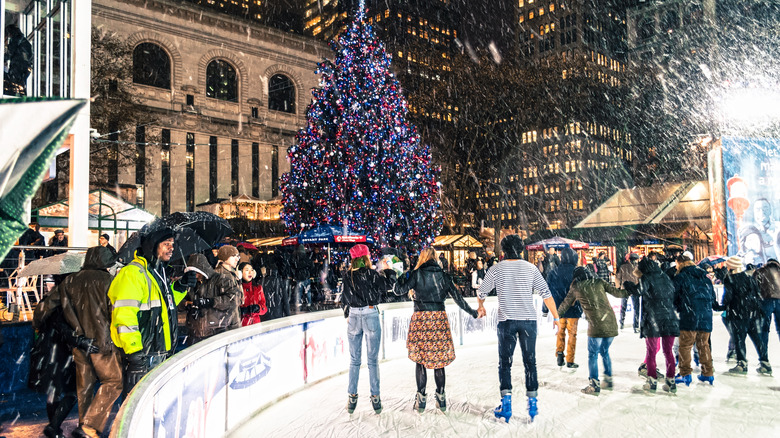 View of ice skating rink with falling snow at Bryant Park Winter Village