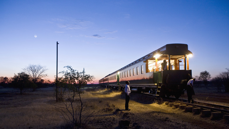 People standing beside the Royal Livingstone Express train at sunset in Zambia