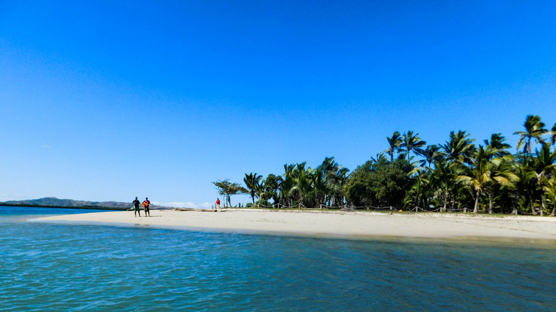 Two ukulele players stand on the sand on a private island in Fiji