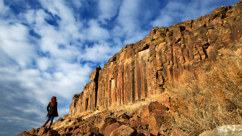 Black Cliffs in Idaho looking brown in direct sunlight with a woman standing on them