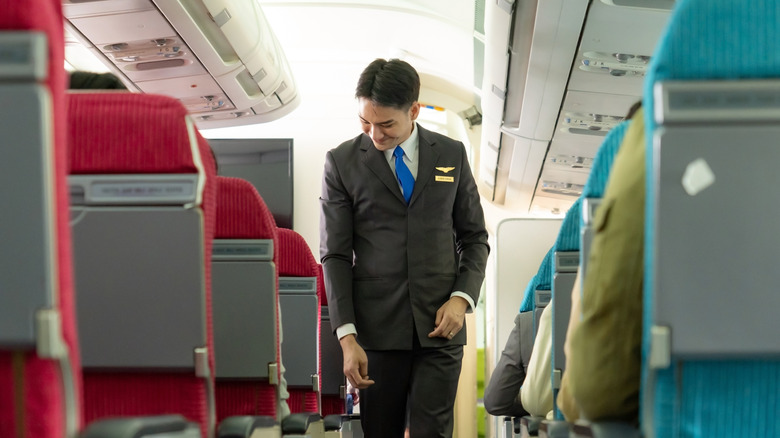 Flight attendant checking seatbelts