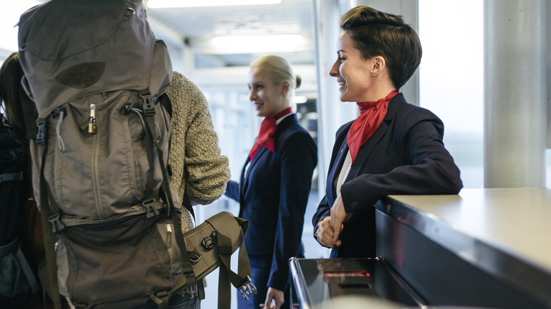 People boarding the plane, walking past flight attendants