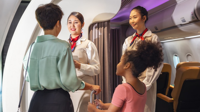 Two flight attendants greet passengers