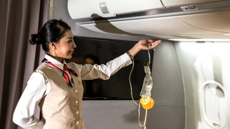 Flight attendant performing a safety demonstration on plane