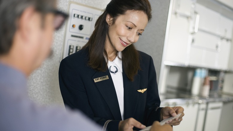 Flight attendant handling the ticket of a passenger