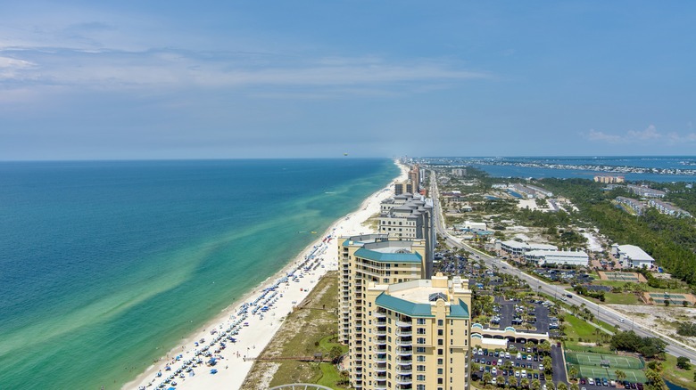 Buildings along a white sand beach