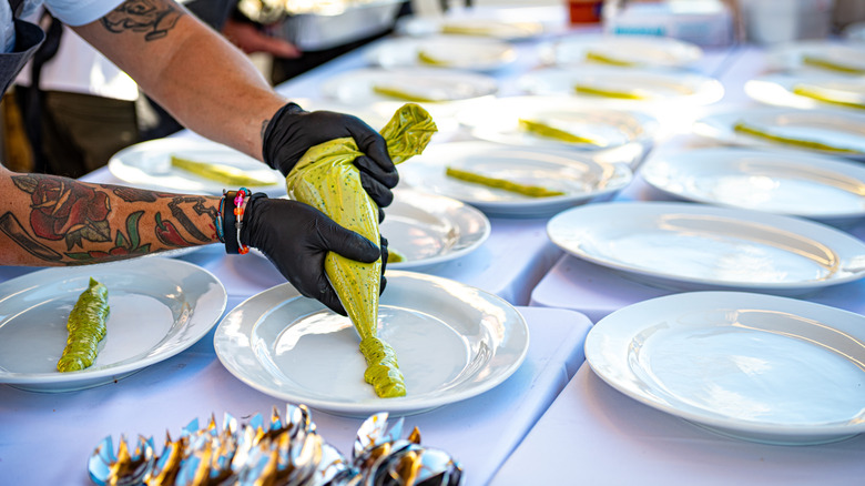 A chef preparing several plates for a catering event