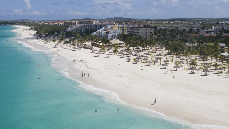 White sand beach with turquoise water and low-rise hotels, Aruba