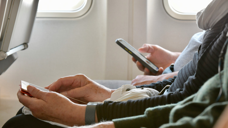 People using devices on plane