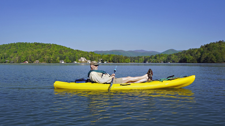 A man lounges while paddling a yellow kayak on Lake Burton in North Georgia