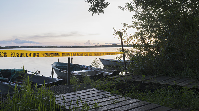 Yellow police tape blocking access to a lake