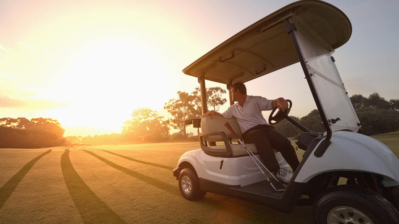 Man watching the sunrise on a golf cart on a range