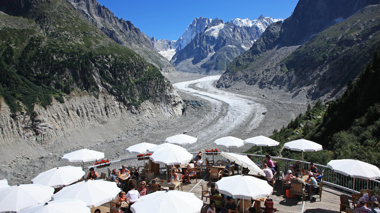 tourists sitting on restaurant terrace overlooking Mer de Glace glacier