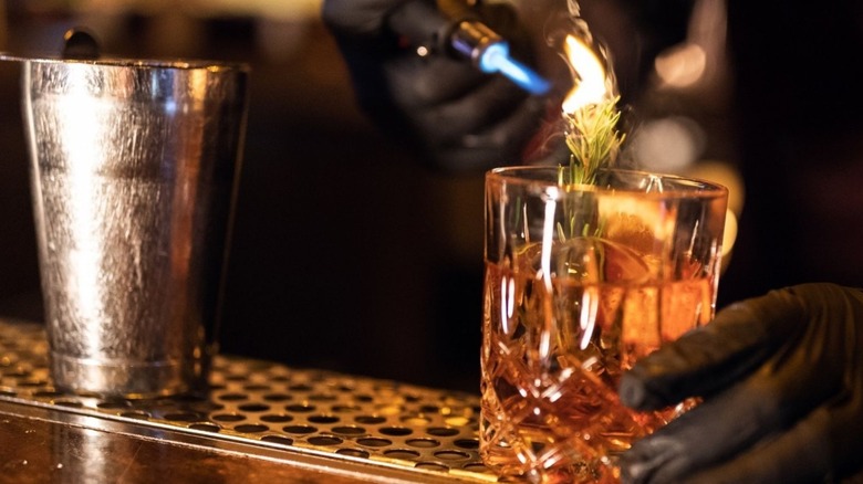 Bar tender holding flame to beverage.