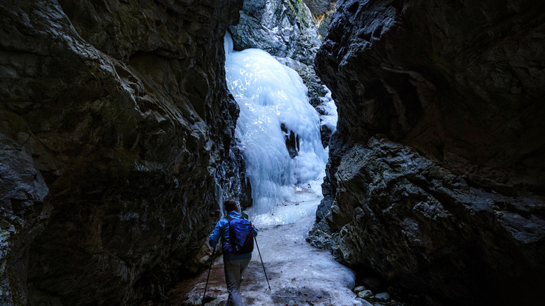 Zapata Falls frozen in the winter with a hiker in a blue jacket