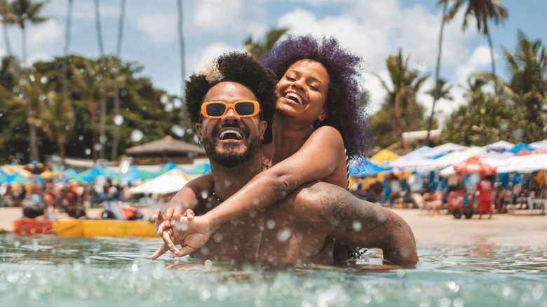 couple smiles and plays in water on Brazilian beach