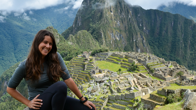 a woman smiles at the top of the Machu Picchu ruins