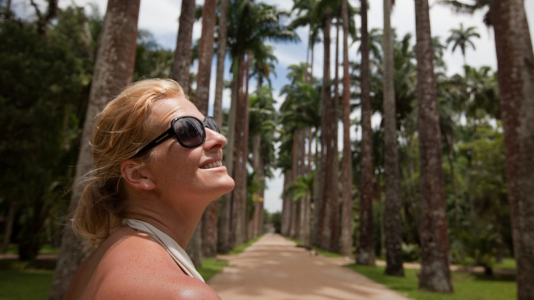 woman looks up and smiles on sunny day in Rio's Botanical Gardens