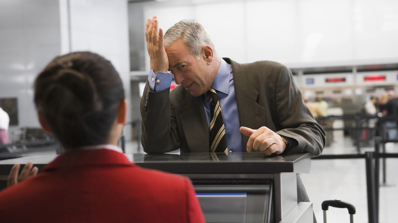 Stressed business traveler looking at airline counter staff