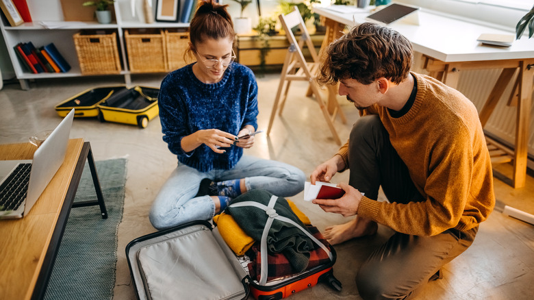 A couple packing suitcases for a trip.