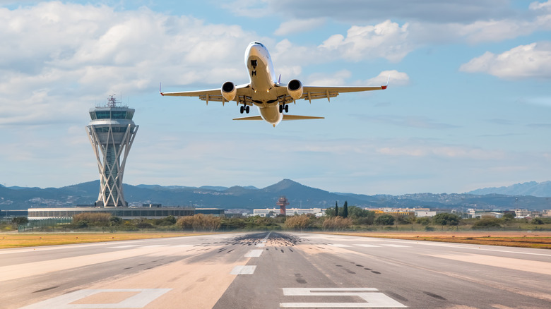 Plane takes off from runway with tower in background