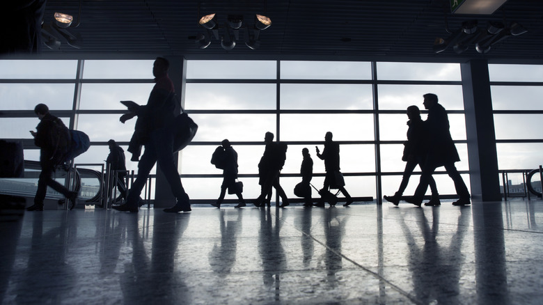 Silhouettes of passengers walking around an airport terminal