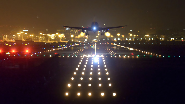 An aircraft landing at the airport runway at night