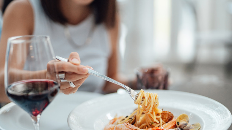 Woman enjoying a glass of wine and a plate of pasta