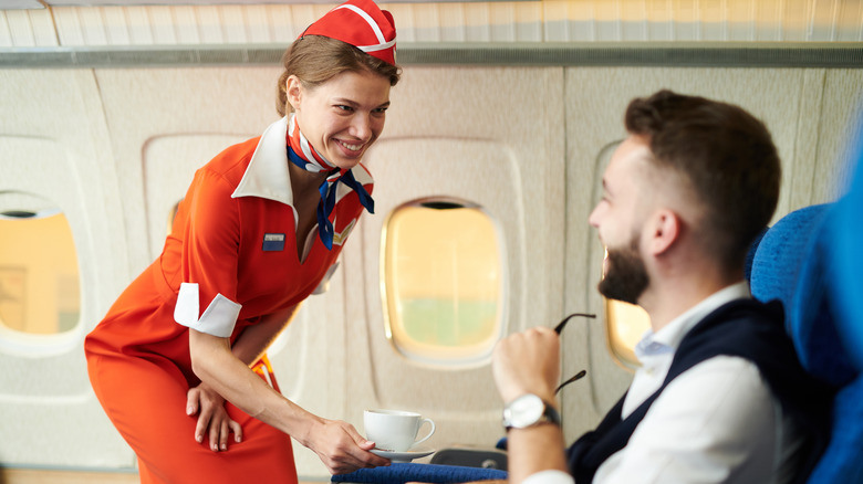 Flight attendant serving a customer in first class