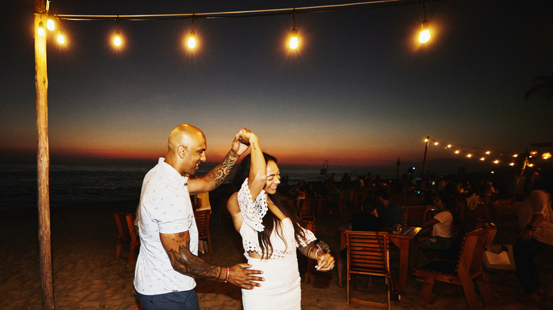 A vacationing couple dances on the beach at night