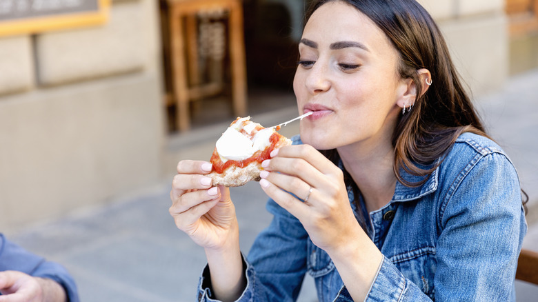 A woman eating a slice of pizza