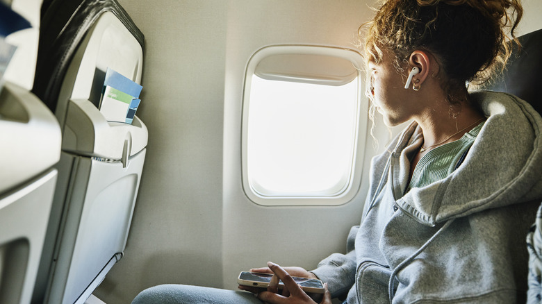 Woman with phone in hand on plane