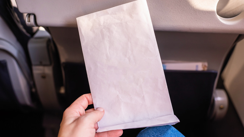 Person holding an air sickness bag