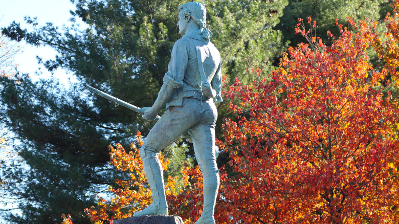 Minuteman statue at Battle Green, Lexington with fall trees in the background