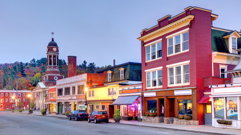 Downtown of Saranac Lake in the Adirondack Mountains, showing two cars in front of a shopping center in the early evening.