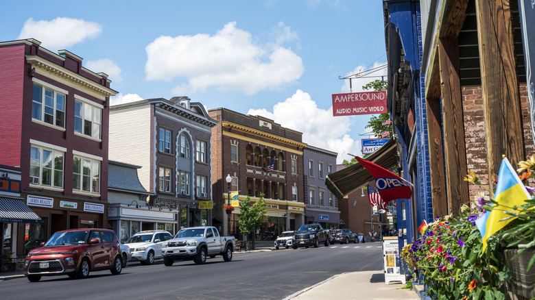 Street view of downtown Saranac Lake in New York, with cars on the street and front of stores showing.