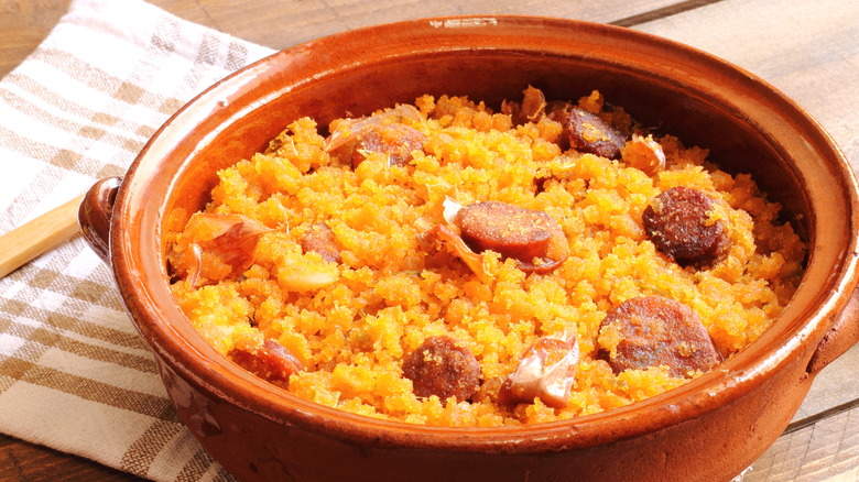 A clay casserole dish with the Spanish dish, migas and chorizo