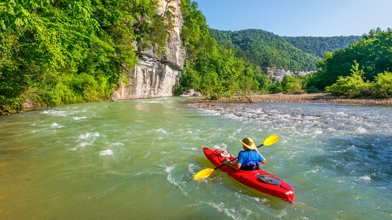 A person kayaking in the rushing rapids of the Buffalo River in Arkansas