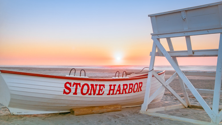 Beach with lifeguard tower and boat reading "Stone Harbor"