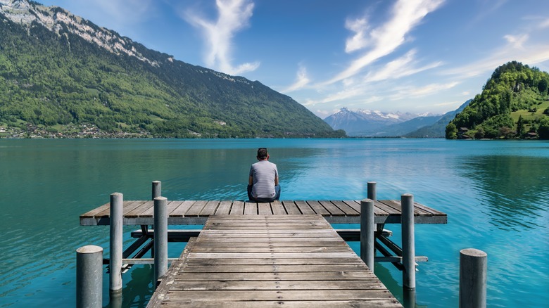 A man sitting on a lake pier